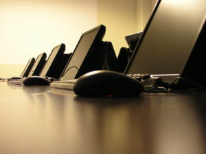 several computer monitors in row with close up of computer mice