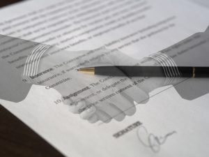 overlay of two hands shaking over signed contract